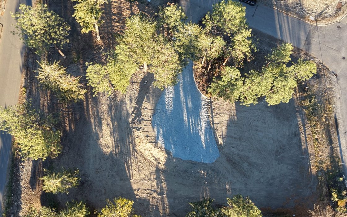 After: the cleared, graded lot among its pines, seen from above