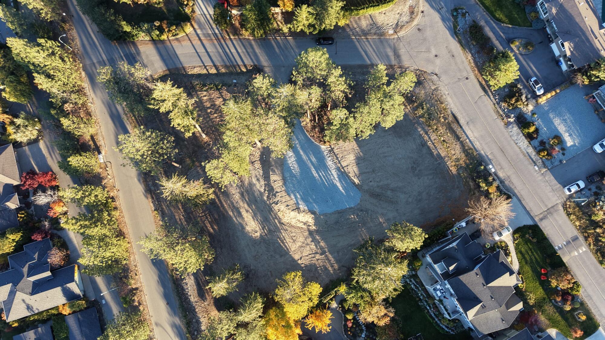 Aerial view of the cleared lot in its established Upper Mission neighbourhood, with Okanagan Lake beyond